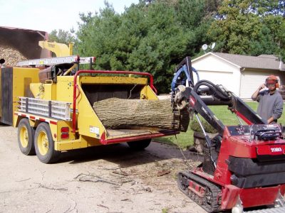 Toro Dingo feeding a chipper with a Branch Manager Grapple (BMG)